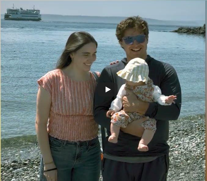 man holding baby with hat, woman looking at baby