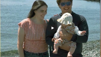 man holding baby with hat, woman looking at baby